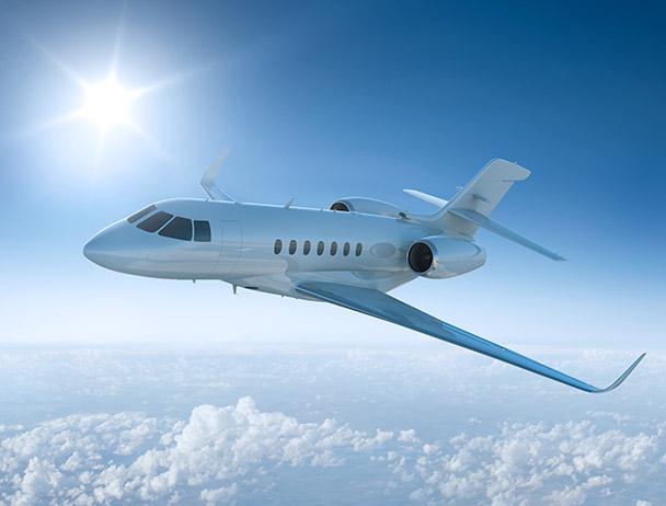 Private business jet flying above the clouds against a sunlit sky